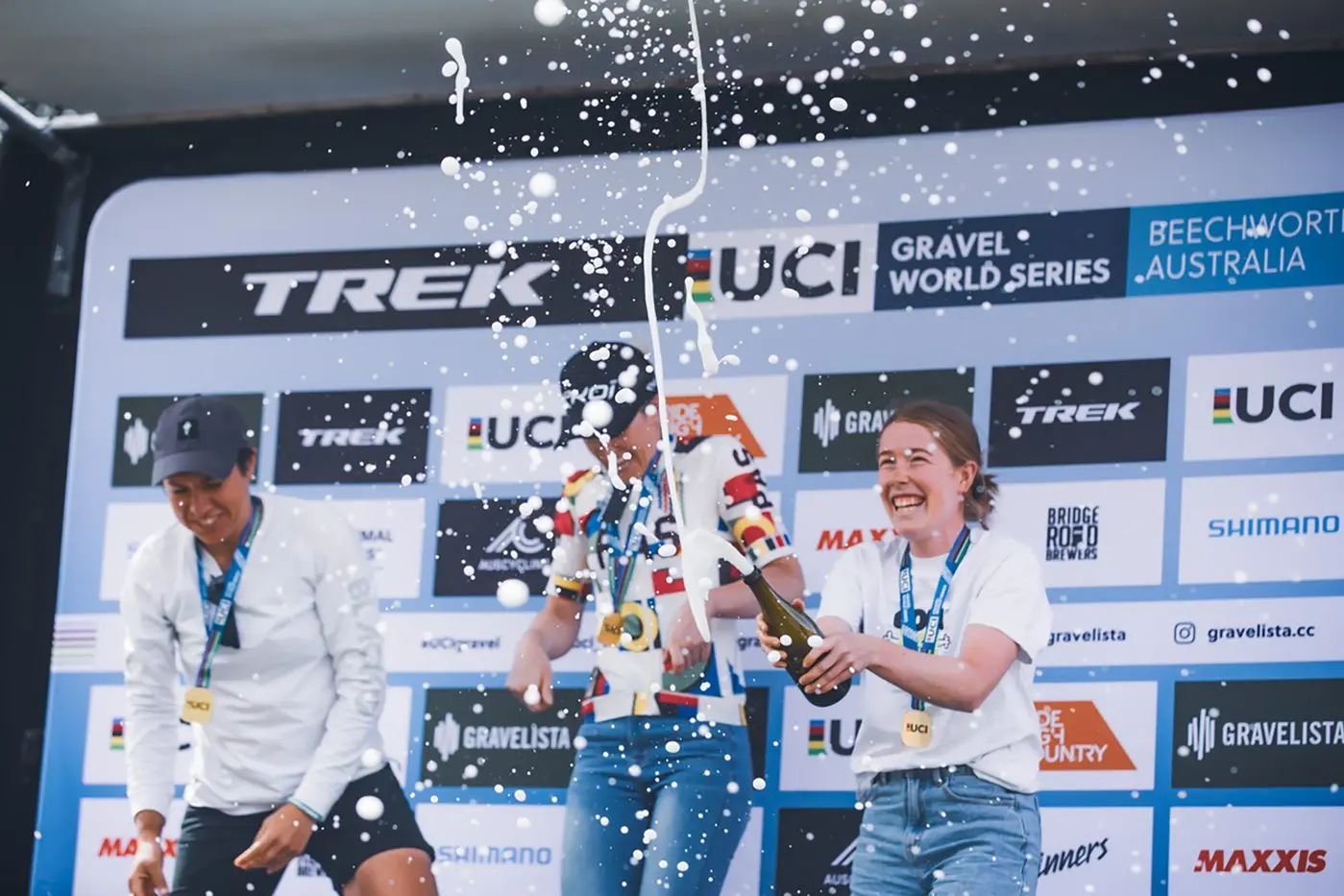 POP THE CORK: Third placed female in the 120km elite UCI event Cassia Boglio gets the podium celebrations rolling with second placed Matilda Raynolds and winner Courtney Sherwell in a wildly successful Gravelista in Beechworth last weekend. PHOTO: Lee Omond