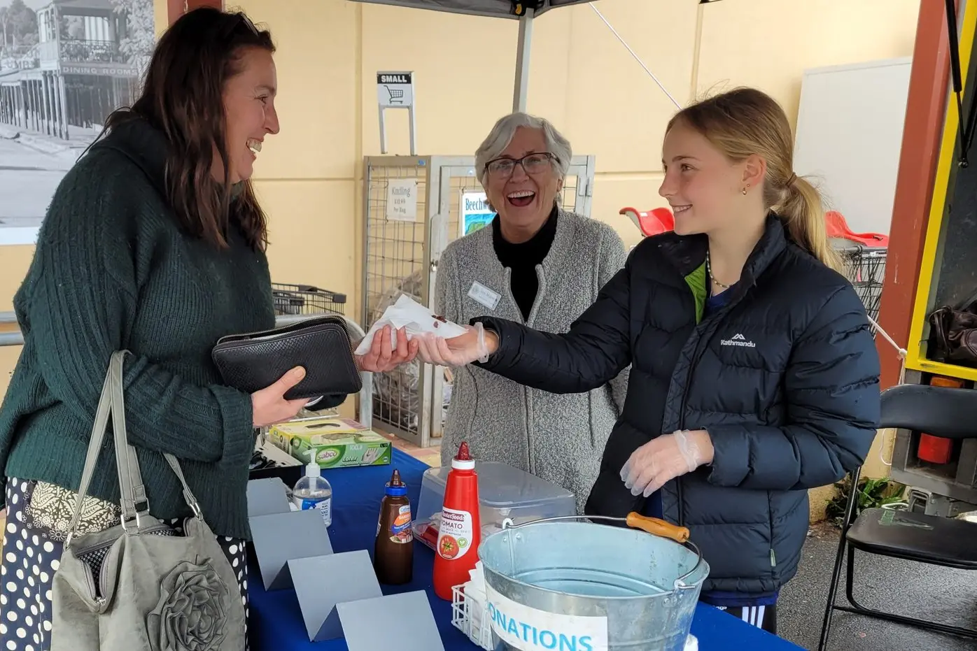 HELPING HAND: Beechworth\\'s Helene Maling buys a sausage from 13\\u2013year\\u2013old hockey player Grace Brown at the Lions fundraiser on Saturday while Iris Mannik (background) looks on. PHOTO: Coral Cooksley. Id:30789